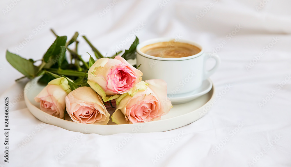 Bed coffee cup with roses bouquet, romantic bed breakfast with flowers and cappuccino coffee cup Bed coffee cup with roses bouquet, romantic bed breakfast with flowers and cappuccino coffee cup