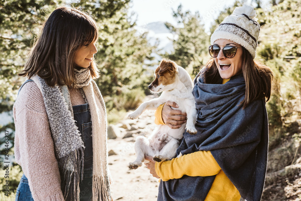 .Two good friends walking through the mountains on a sunny winter day, accompanied by their sweet brown and white dog. Dogfriendly. Lifesytle. .Two good friends walking through the mountains on a sunny winter day, accompanied by their sweet brown and white dog. Dogfriendly. Lifesytle.