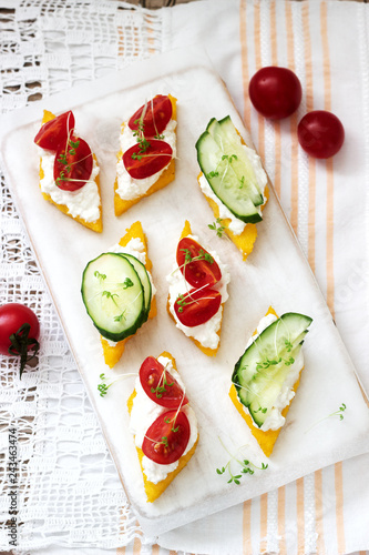 Vegetarian canapes from polenta with cheese, vegetables and cress on a light background. Rustic style. photo