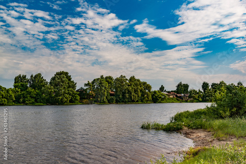 Landscape  beautiful summer. A village on the Bank of a wide river  beautiful  Cumulus clouds on a blue sky on a summer day.