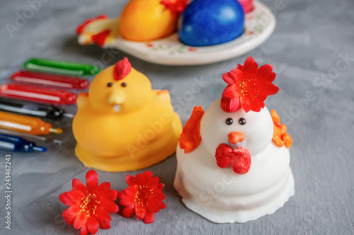 Multi-colored Easter eggs lie next to paint for coloring and marzipan Easter cakes in the shape of chickens © oksanamedvedeva