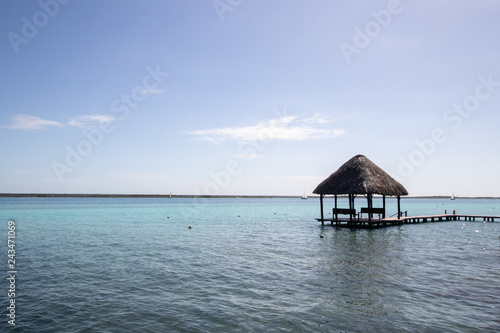 Fototapeta Naklejka Na Ścianę i Meble -  blue and blue Caribbean sea with crystal clear waters and clear sky. a bungalow with a pier in the middle of the lagoon in a coral reef. hotel and rooms by the sea