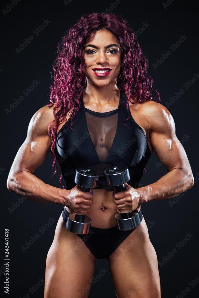 Obraz premium Sporty fit woman, athlete, egyptian and muslim with dumbbells makes fitness exercising on black background with lights.