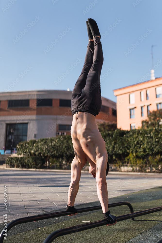 Young man doing handstand exercises on parallel bars