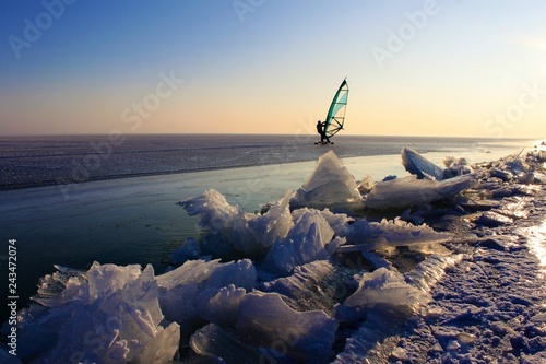 eissurfen auf zugefrorenem see im winter/sport am eis, abendliche stimmung am neusiedlersee in österreich/segel, himmel, schnee, alleine im schnee, blick auf die weite des horizonts
