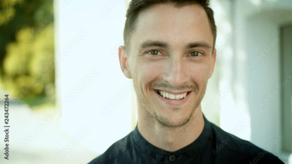Portrait of smiling young man enjoying spending free time in city park. Cute caucasian brunette guy looking at camera Portrait of smiling young man enjoying spending free time in city park. Cute caucasian brunette guy looking at camera