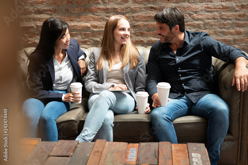 Attractive co workers talking sitting on sofa during break