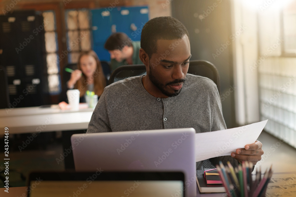 Young attractive black man looking over documents in modern office Young attractive black man looking over documents in modern office