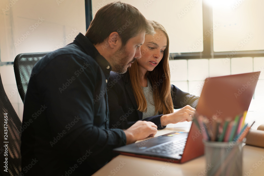 Work colleagues going over presentation on computer in modern office Work colleagues going over presentation on computer in modern office