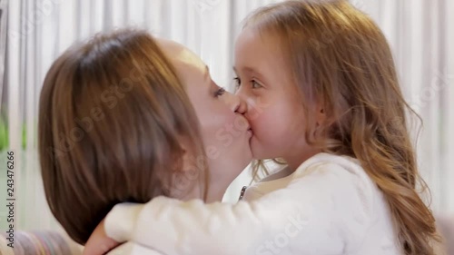 Close-up - Pretty Mother And Charming Daughter Hugging And Kissing While Sitting In A Cozy Home. Concept Of Child Care And Protection Of Motherhood And Childhood