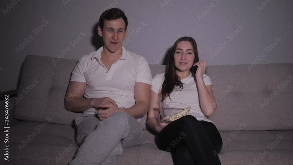 Happy couple watching a movie on tv sitting on a couch at home Happy couple watching a movie on tv sitting on a couch at home