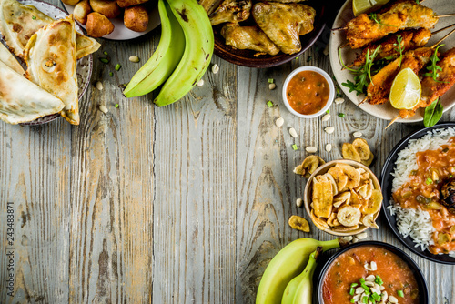 West african food concept. Traditional Wset African dishes assortment - peanut soup, jollof rice, grilled chicken wings, dry fried bananas plantains, nigerian chicken kebabs, meat pies, top view photo