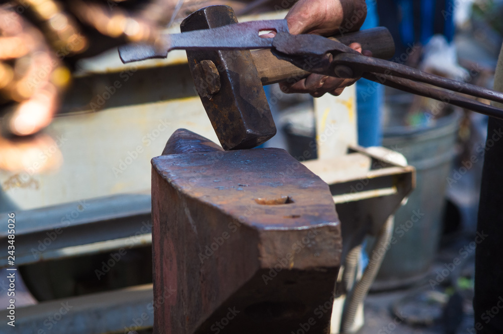 blacksmith performs the forging of hot glowing metal on the anvil blacksmith performs the forging of hot glowing metal on the anvil