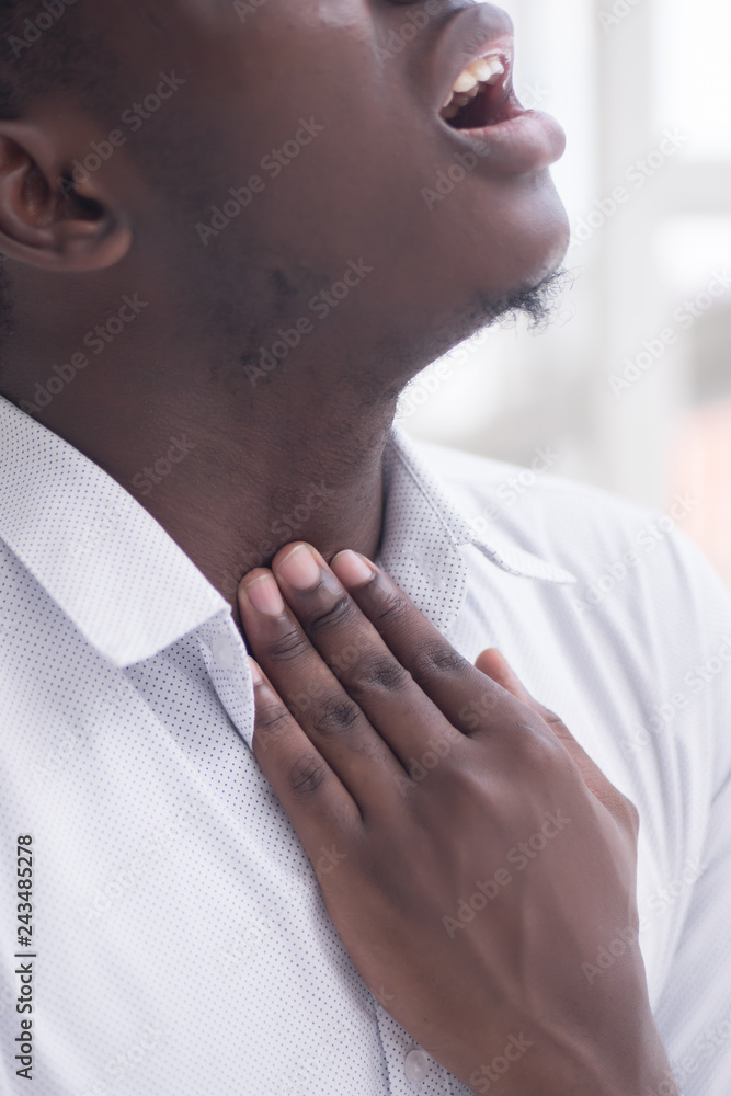 Sick African man with sore throat; Portrait of ill black man suffering