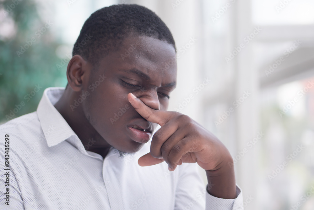 Sick African man with runny nose; Portrait of ill black man suffering