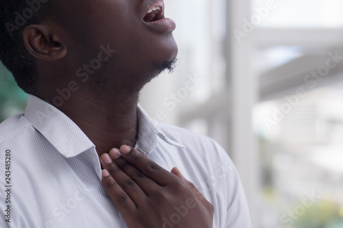 Sick African man with sore throat; Portrait of ill black man suffering from sore throat due to cold, flu, allergy, polluted air, dust, smog; air pollution sickness concept; African man model photo