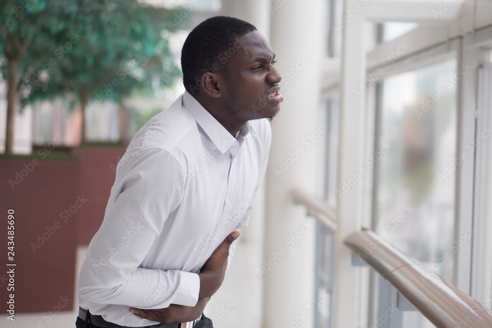 African man suffers from stomachache; sick black man with stomachache