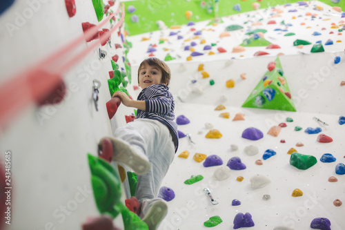 Sweet little preschool boy, climbing wall indoors