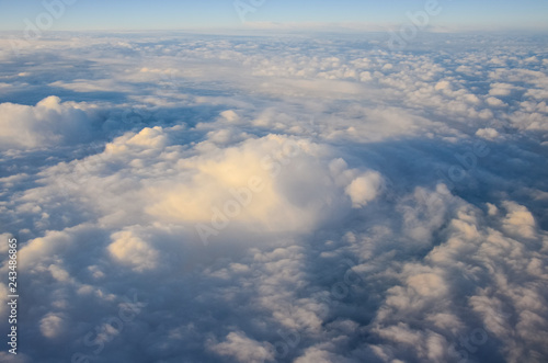 Airplane flying above clouds at sunrise. Aerial window view