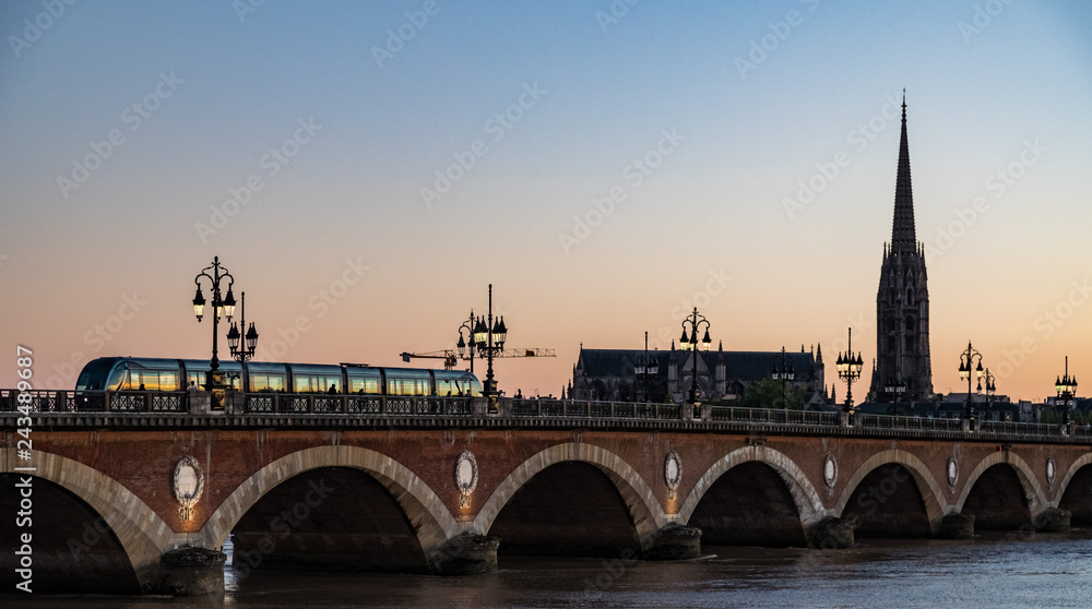 Naklejka premium Tram crossing Pont de Pierre bridge in the city of Bordeaux at sunset