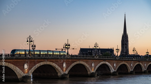 Tram crossing Pont de Pierre bridge in the city of Bordeaux at sunset