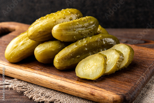 Obraz na plátně Pickled cucumbers on dark wooden background.