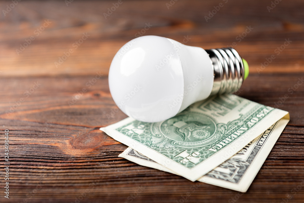 Bulb and dollar money on dark wooden background. Bulb and dollar money on dark wooden background.