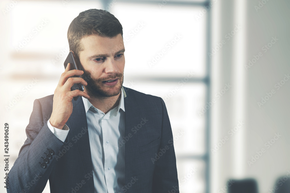 business communication - young businessman talking on the phone in office