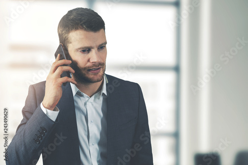 business communication - young businessman talking on the phone in office