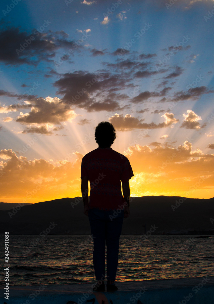 Man standing firm looking at the horizon at sunset.