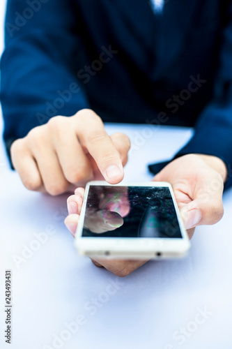 Close up of shot of single hand of a business man wearing a blue colored suit isolated on white using a smart phone with single hand concept of working on a project at a time.