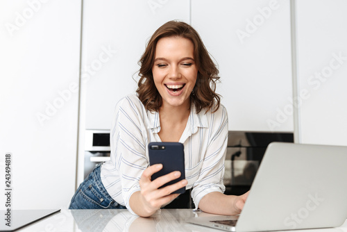 Happy young businesswoman standing at the kitchen