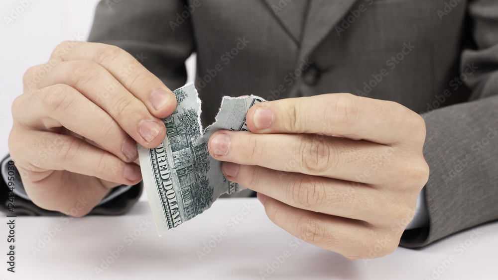 closeup.businessman tearing a dollar bill sitting behind a Desk. closeup.businessman tearing a dollar bill sitting behind a Desk.