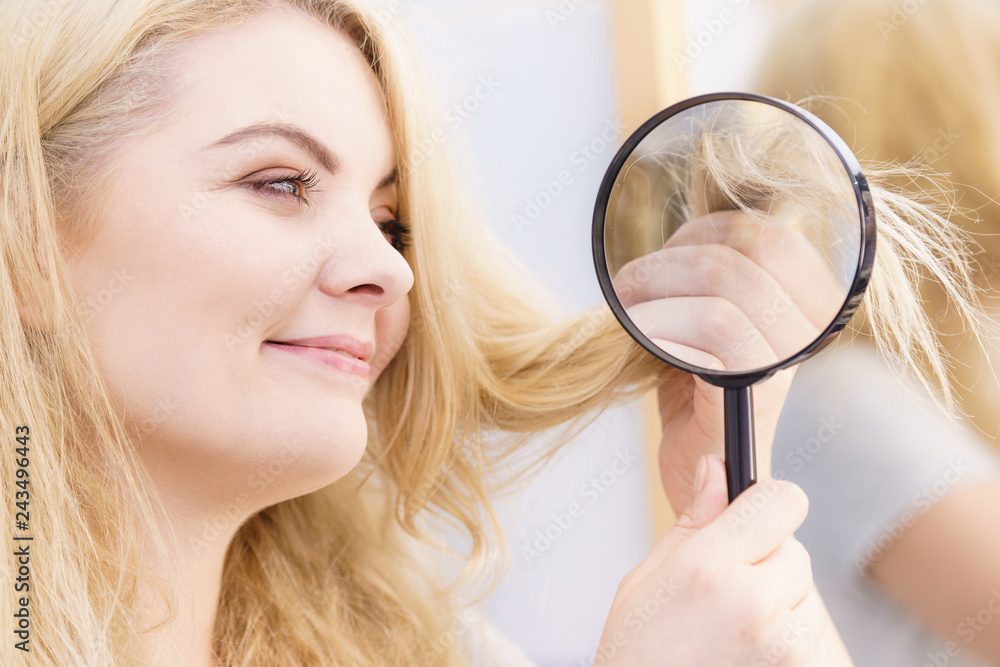 Happy woman looking through magnifer at hair Happy woman looking through magnifer at hair
