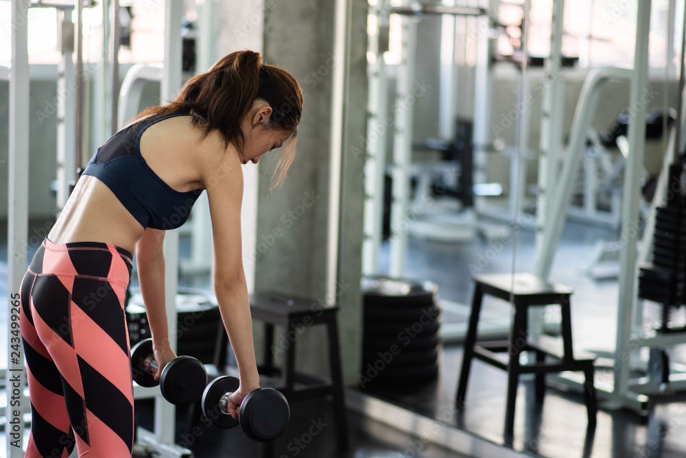 Fototapeta premium Fitness woman in training exercises with dumbbells.