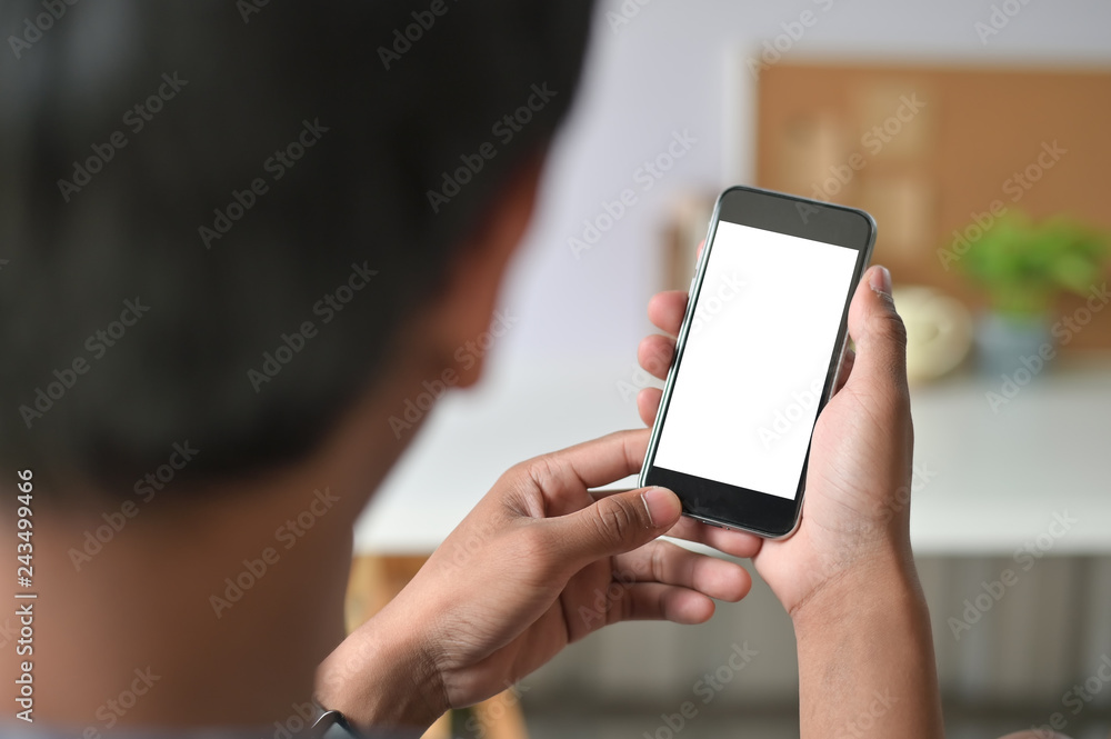 Man hands holding smart phone with blank copy space screen for your text message or information content, male reading text message on telephone during in office desk urban setting.