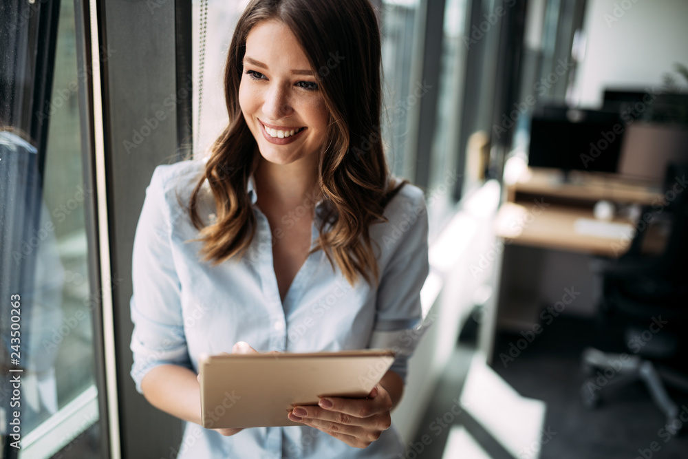 Happy woman manager holding tablet and standing in modern office Happy woman manager holding tablet and standing in modern office