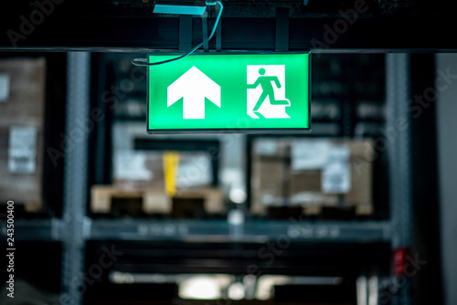 Green emergency exit sign or fire exit sign showing the way to escape with arrow symbol.