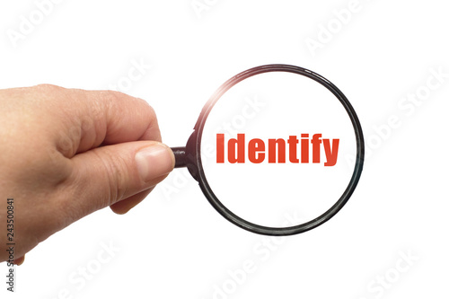Magnifying glass in hand and a identify word on the white background photo