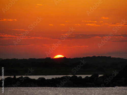Sunset with a orange red and yellow sky in a river ocean lake sea 