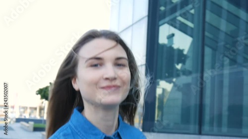 Charming young woman with a magnificent long blond hair and blue eyes turns to camera and smiles