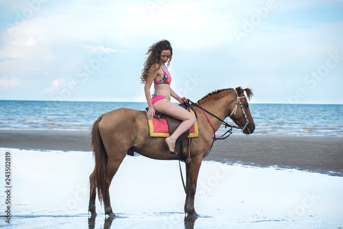 Pretty young lady riding a horse on the beach background of the sea