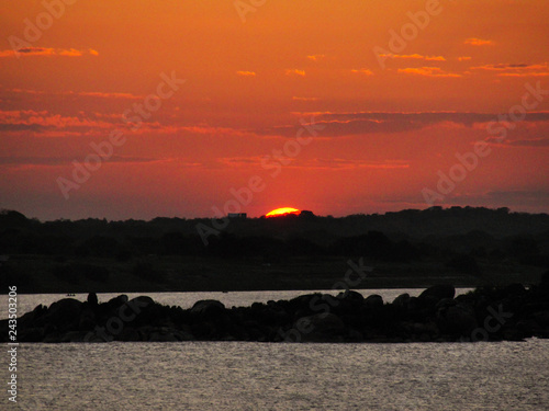 Sunset with a orange red and yellow sky in a river ocean lake sea 