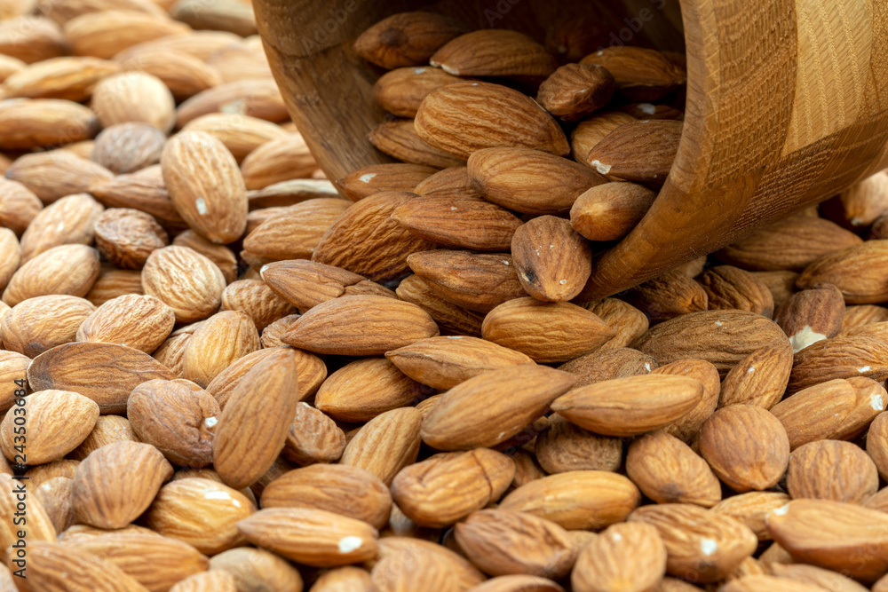Almonds spilling out of wooden bowl Almonds spilling out of wooden bowl