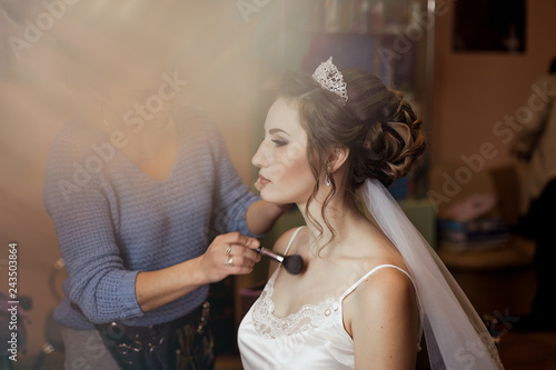 Make-up artist doing makeup to the bride on the wedding day. large portrait. applying blush brush.