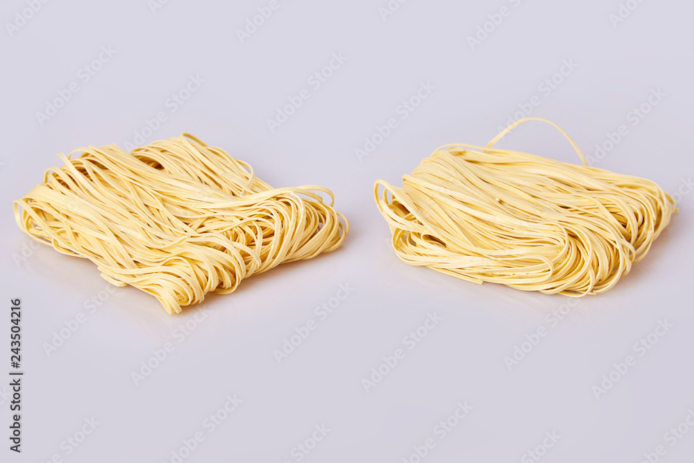Dry thin rolled noodles square shape. Capelli d'angelo, Angel's hair - pasta. Homemade italian pasta tagliatelle. Italian Cuisine. Egg noodles. Pasta tagliatelle nest isolated on white background Dry thin rolled noodles square shape. Capelli d'angelo, Angel's hair - pasta. Homemade italian pasta tagliatelle. Italian Cuisine. Egg noodles. Pasta tagliatelle nest isolated on white background