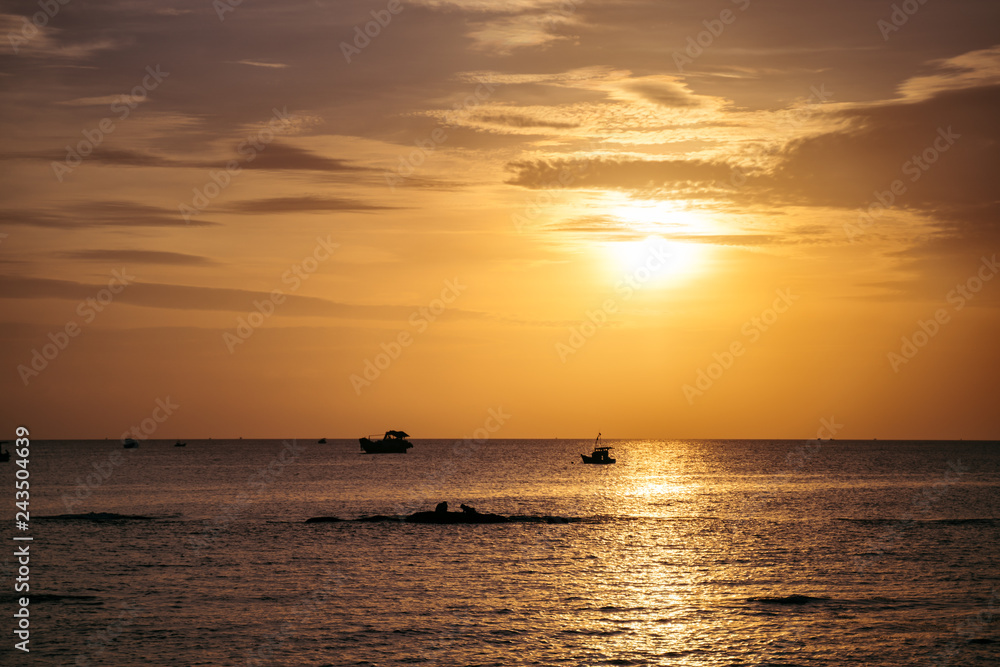 Dramatic sunset clouds reflected on the water sea. Tropical landscape at golden hour