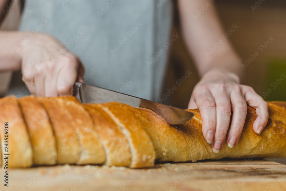 Closeup of housewife preparing snack - tapas and sandwiches - home cooking - step 2 cut baguette