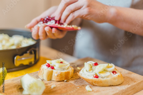Closeup of housewife preparing snack - tapas and sandwiches - home cooking - step 16 add quail egg and decorate with pomegranate