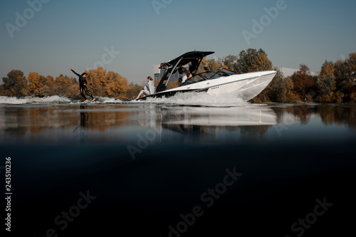 Girl riding on the wakeboard on the high wave of the motorboat photo